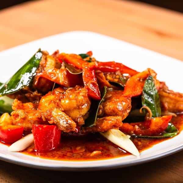 Pattaya Kitchen's spicy Thai dish with shrimp, red peppers, green leaves, and a rich sauce.