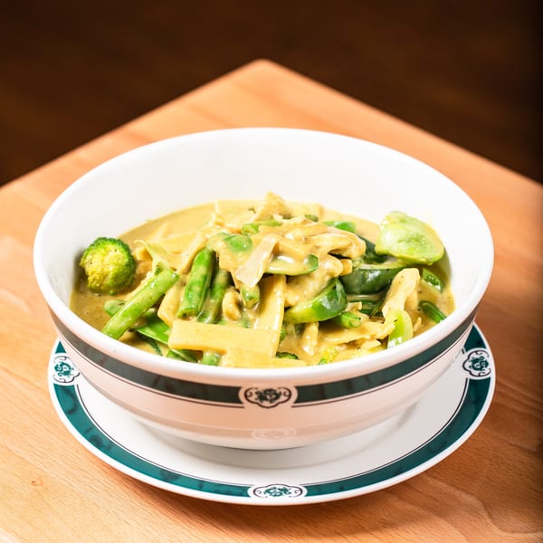 Pattaya Kitchen's yellow curry with chicken, broccoli, green beans, and bell peppers in a white bowl.